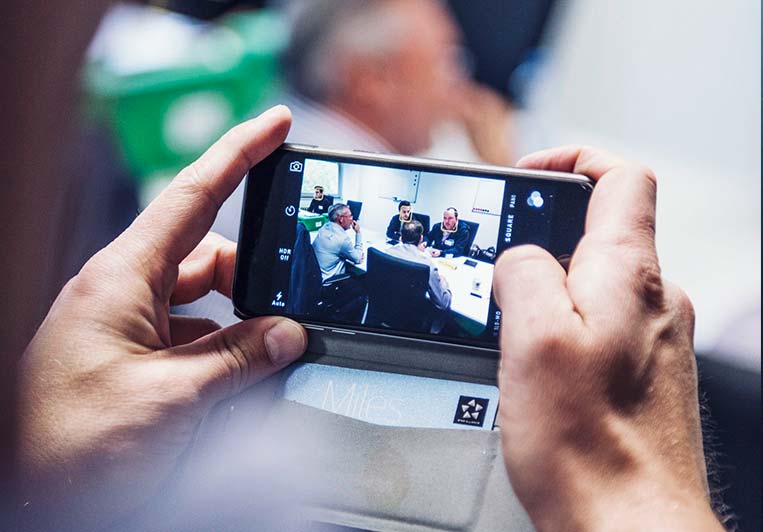 Blick auf ein Smartphone auf dem ein Foto einer Grupperarbeit zu sehen ist (photo)